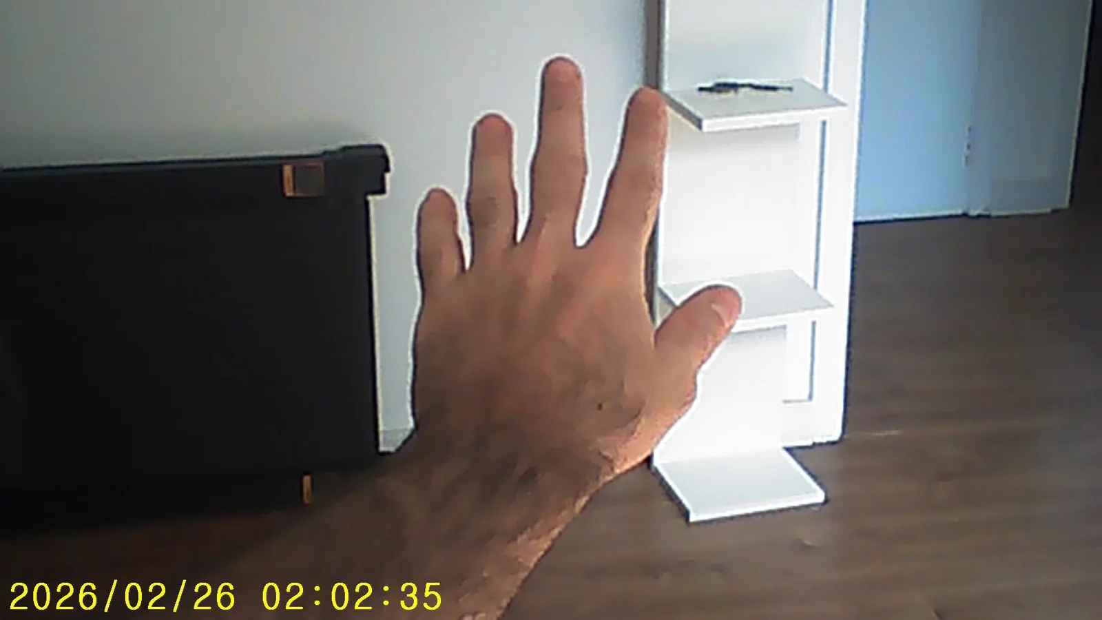 Mão levantada diante de uma janela iluminada
