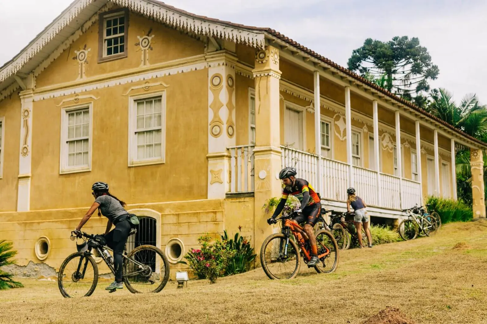 Ciclistas passam diante de um casarão histórico amarelo