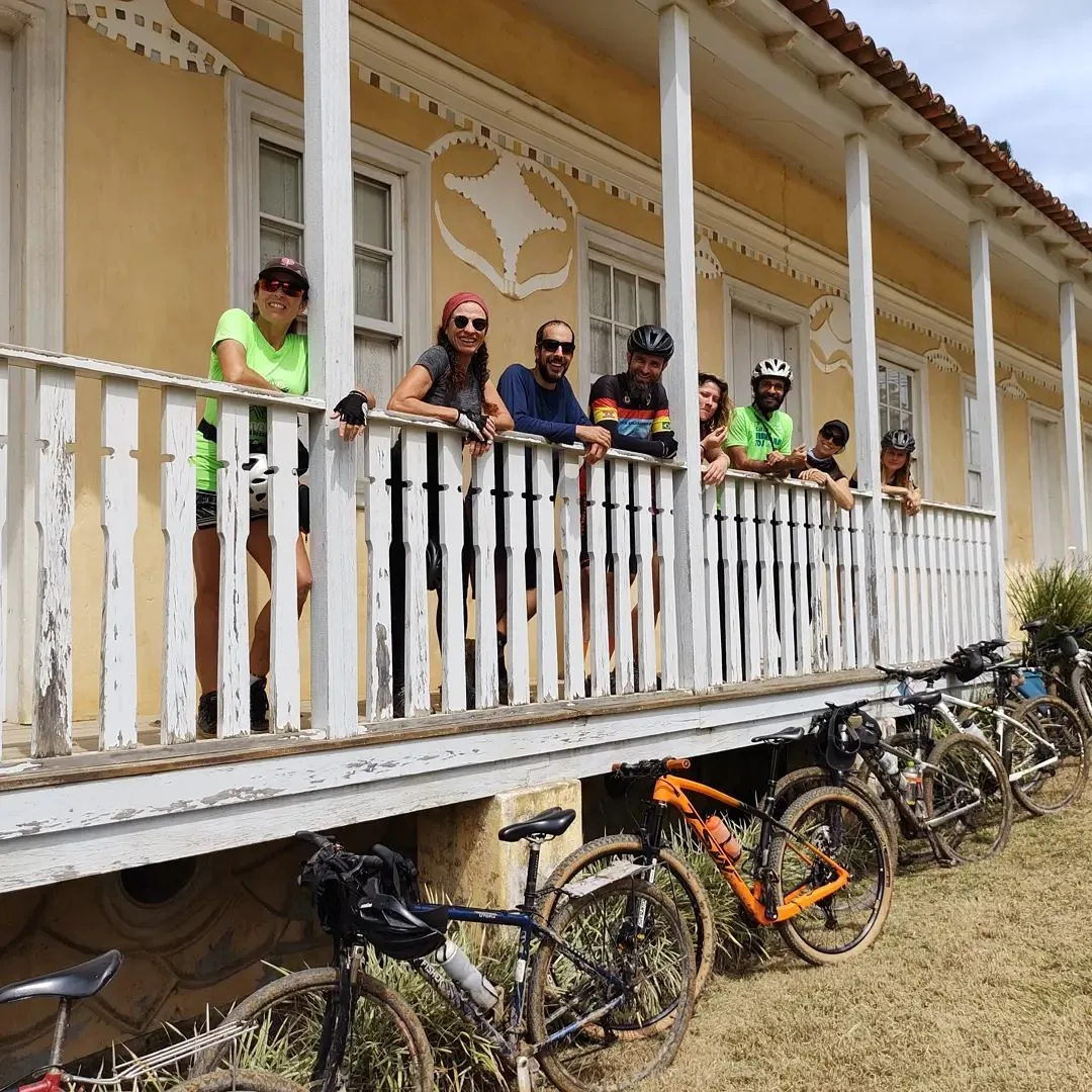 Ciclistas na varanda do Casarão Campo de Demonstração com bicicletas apoiadas abaixo