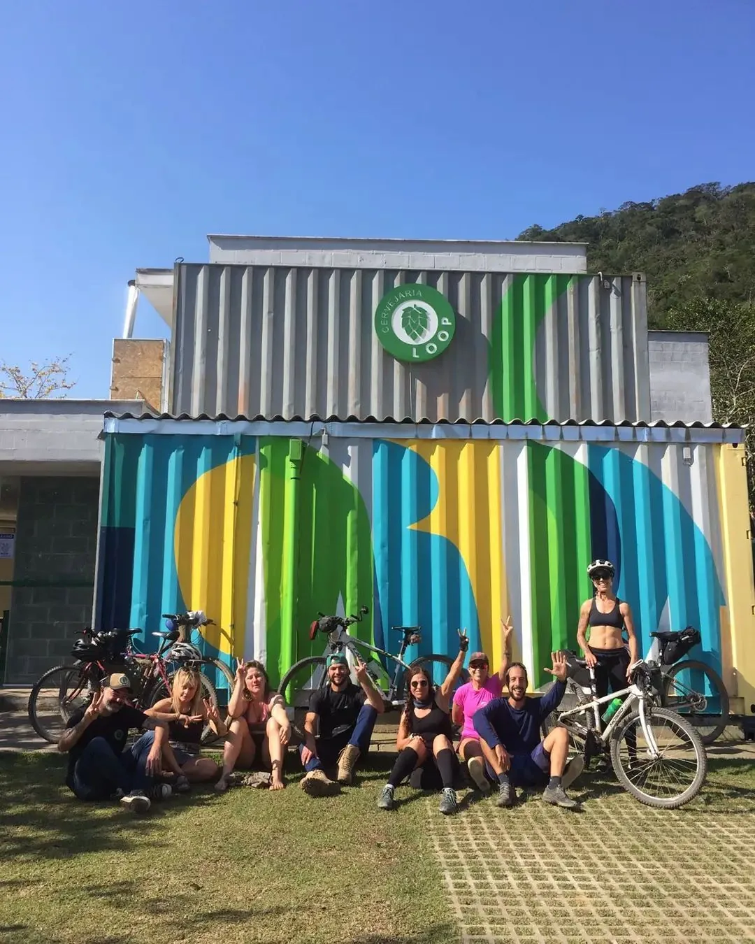 Grupo de ciclistas diante do mural colorido da Cervejaria Loop