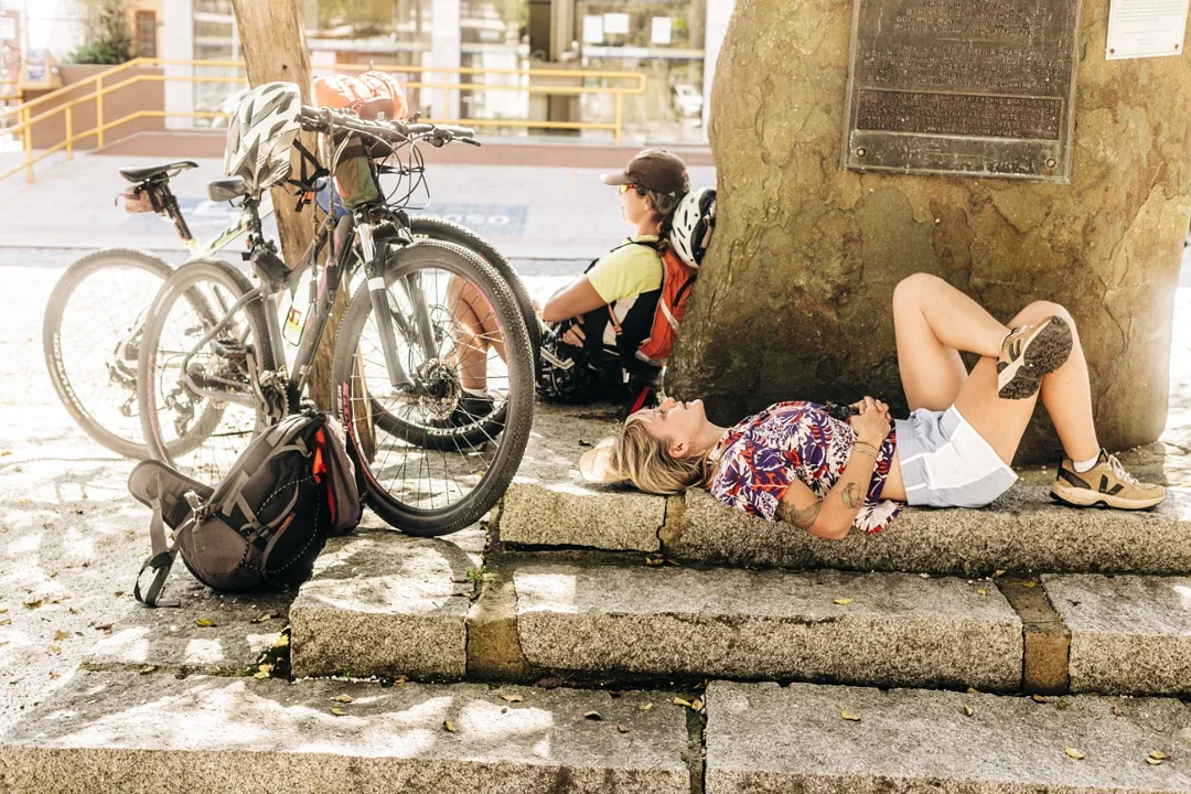 Bicicletas e ciclistas descansando sob a sombra das árvores em um dia de calor