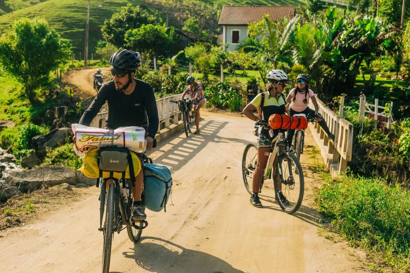 Ciclistas empurram e pedalam bicicletas em uma subida rural