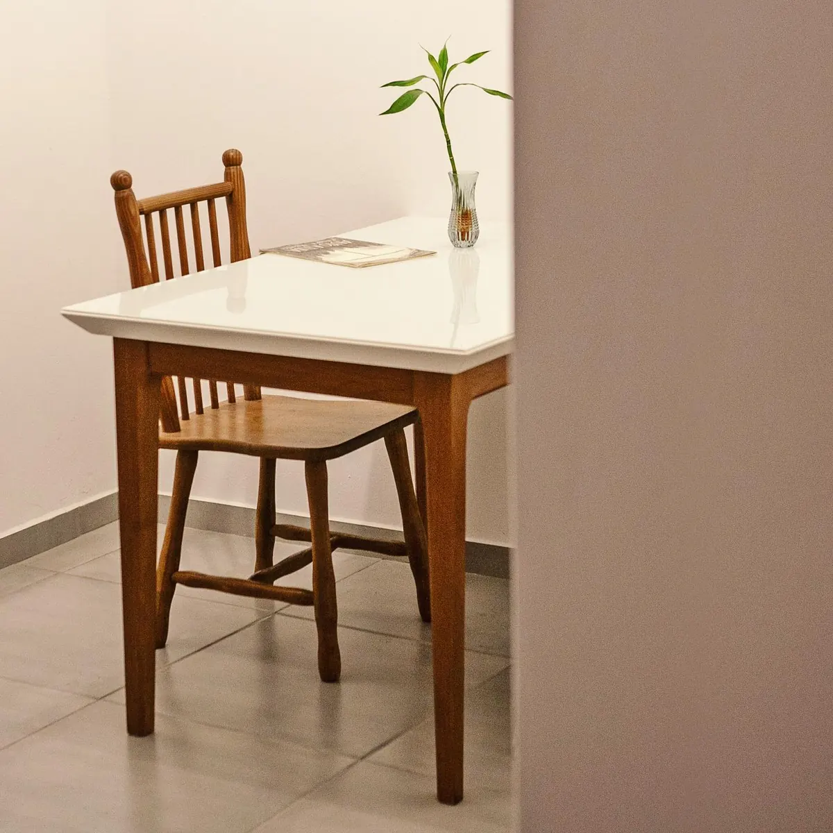 Mesa branca, cadeira de madeira e uma garrafa com planta no apartamento 403