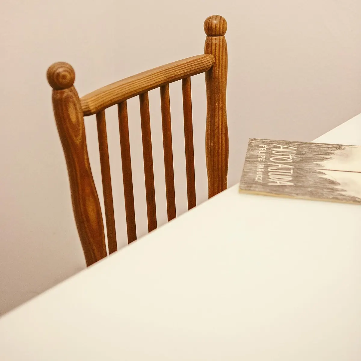 Cadeira de madeira encostada na mesa branca do apartamento 403