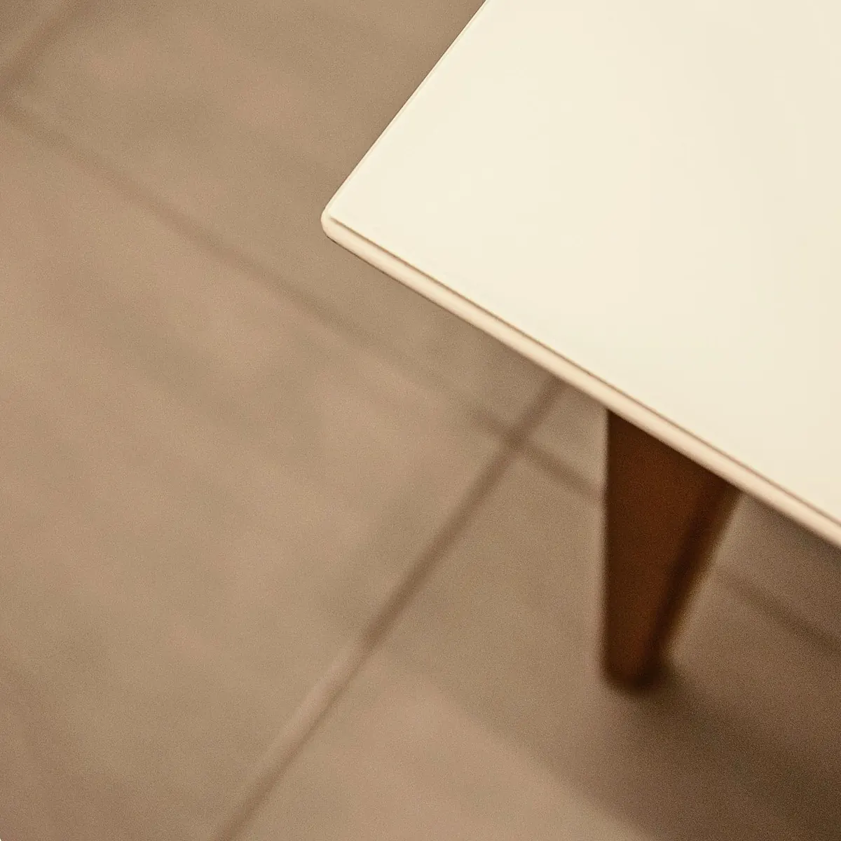 Detalhe do encontro entre mesa branca, piso claro e cadeira no apartamento 403