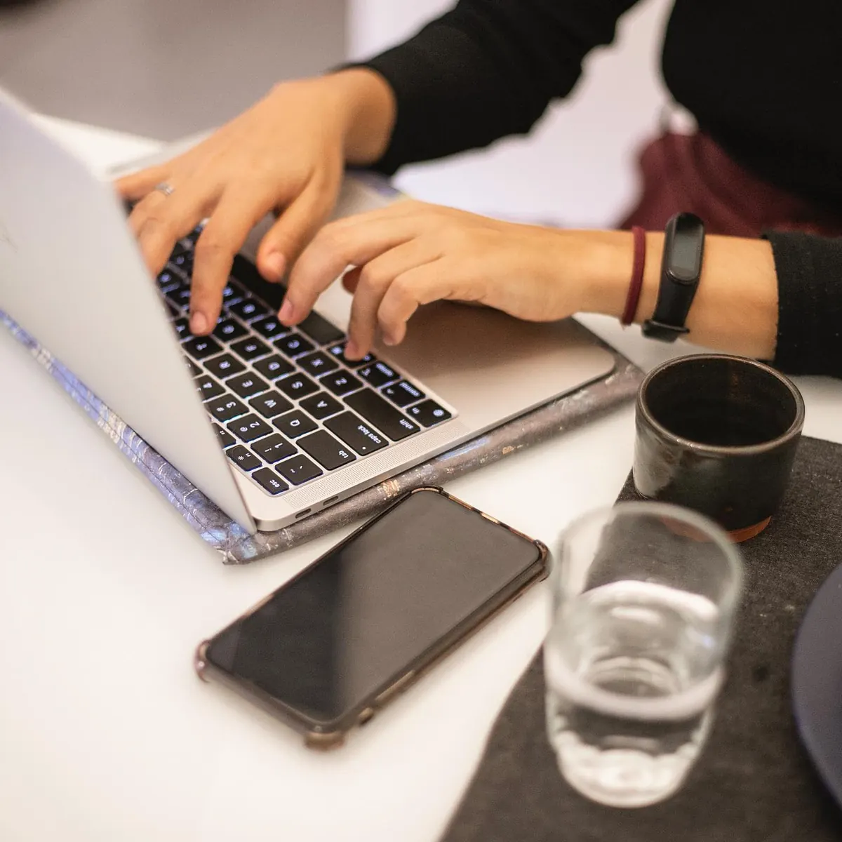 Mesa com notebook, celular, copo e mão em movimento no apartamento 403