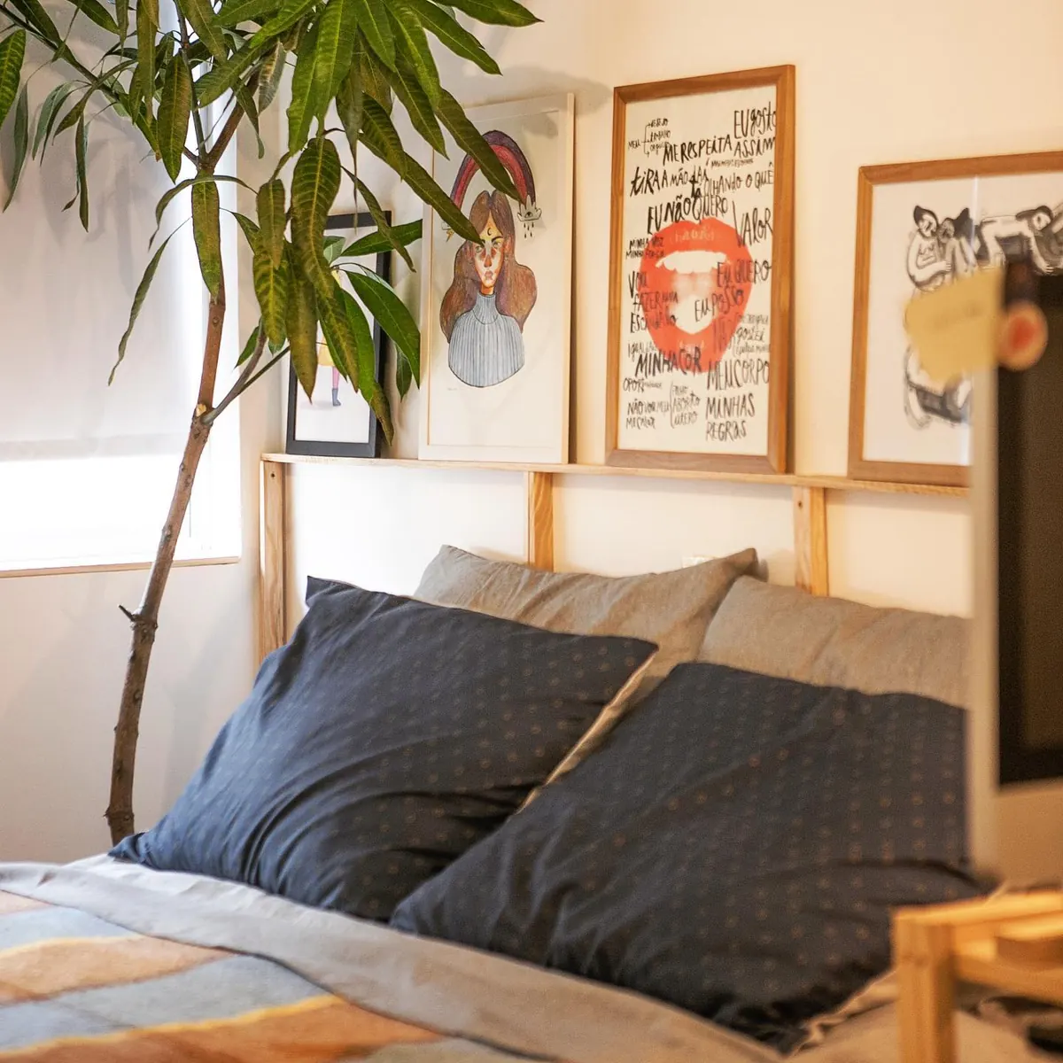 Cama arrumada com travesseiro azul e quadros na parede do apartamento 403