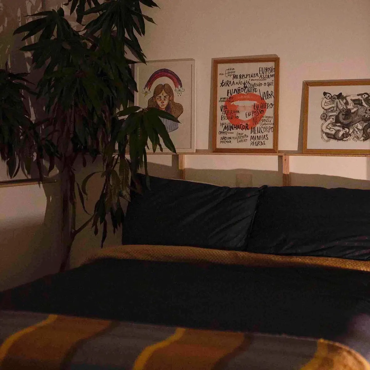 Cama e quadros fotografados em luz baixa no apartamento 403