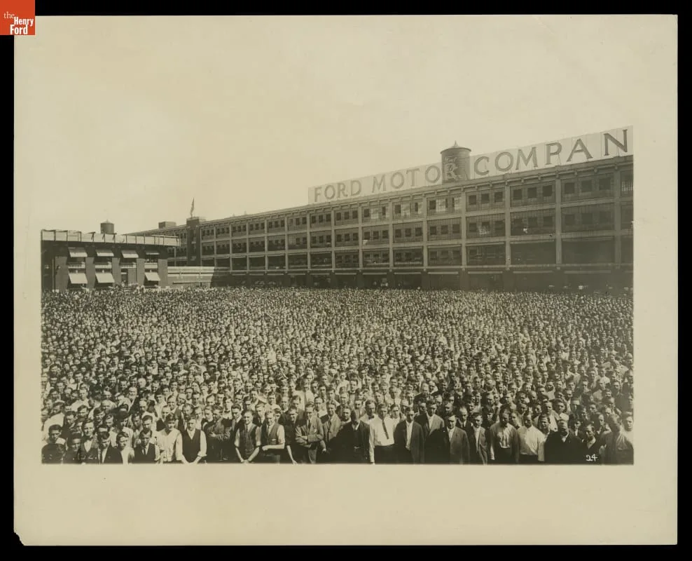 Multidão de trabalhadores da Ford reunida diante da planta de Highland Park em 1913, posando para uma fotografia panorâmica