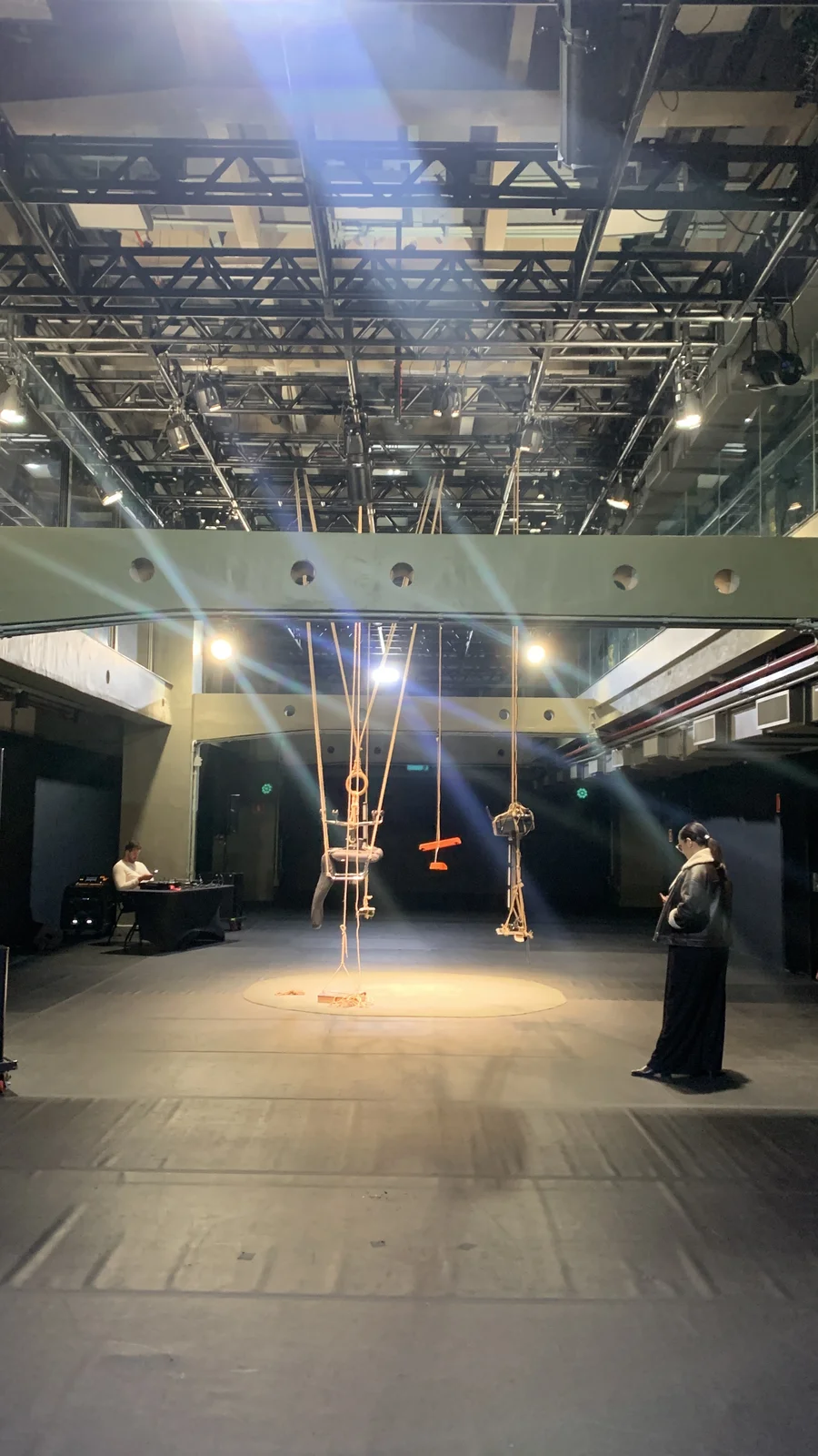 A cena montada, objetos de escritório suspensos por cordas no centro da sala, antes do início da performance
